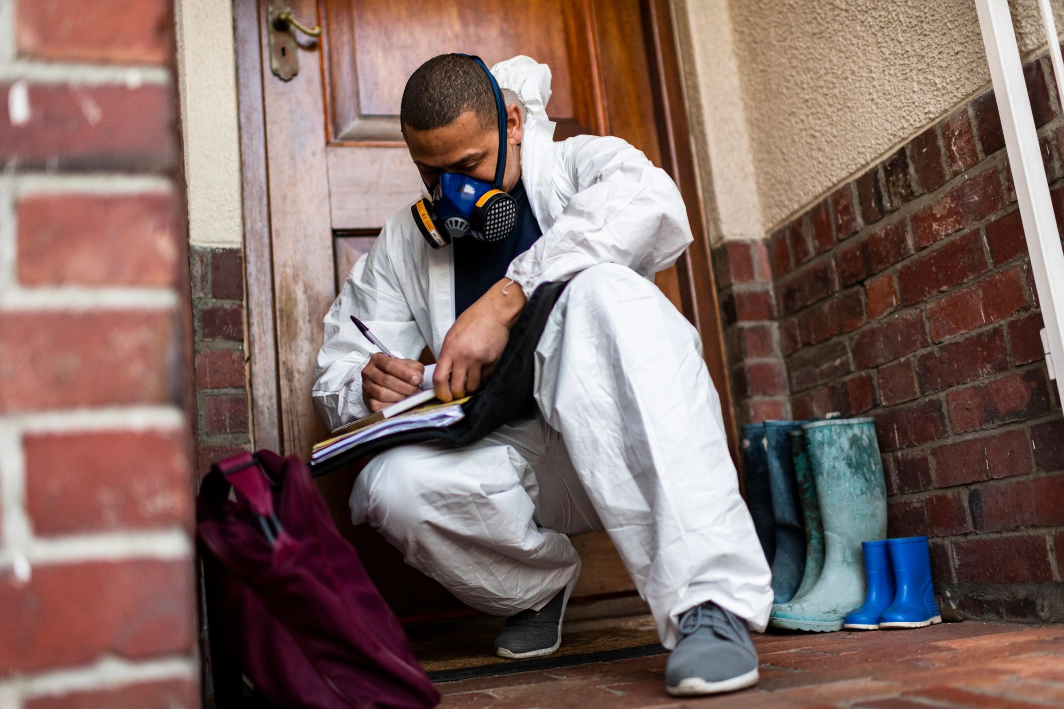 Front line worker in PPE filling out forms after decontaminating a home
